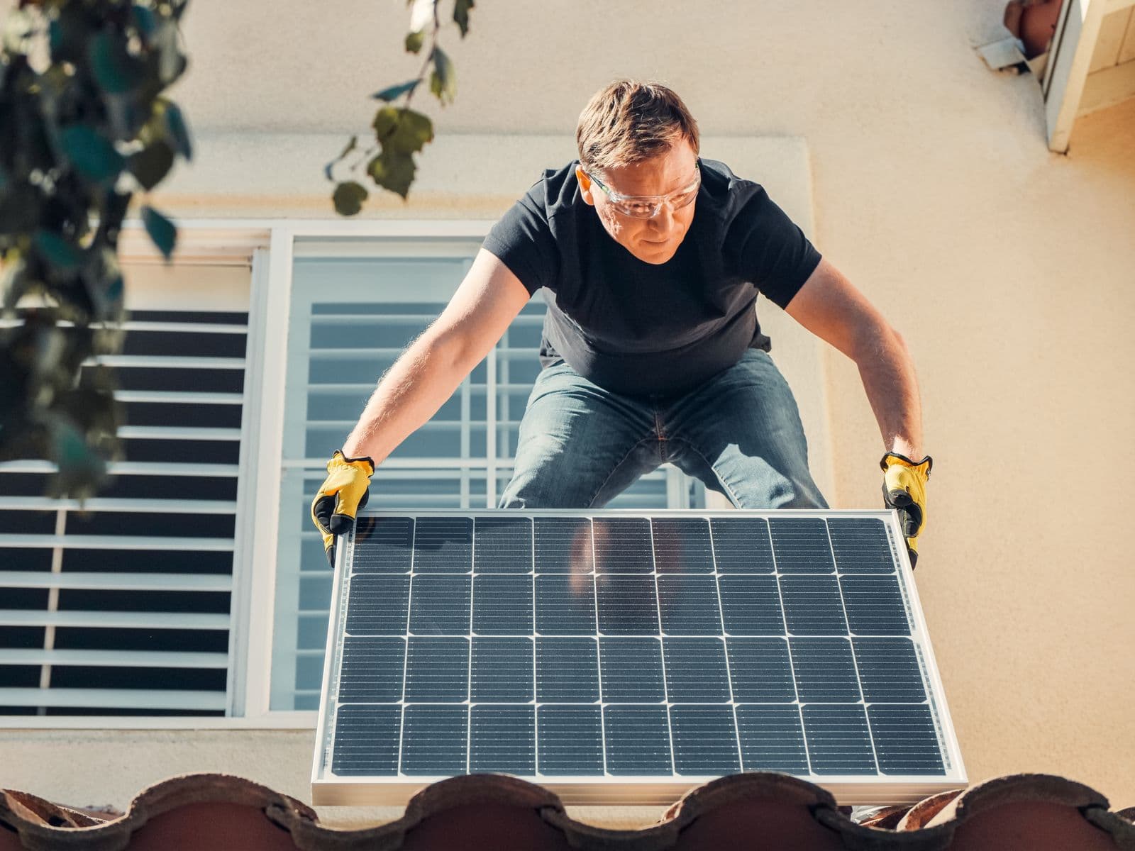 Solar installer in safety glasses mounting a photovoltaic panel on a residential roof in the Waco area